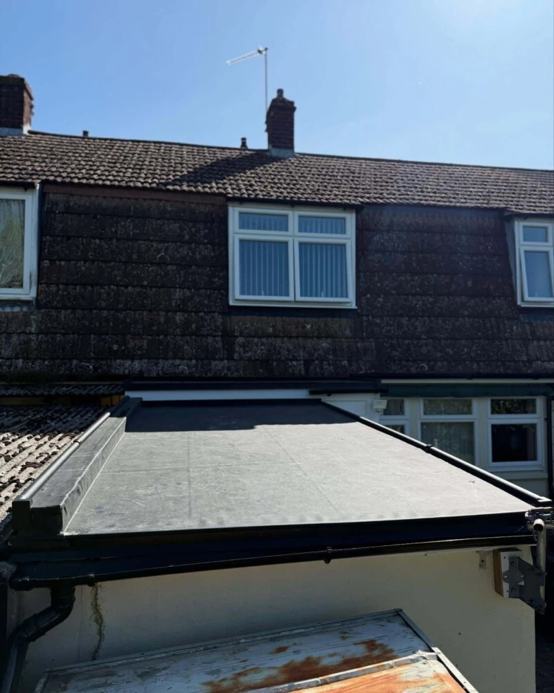 New grey flat roof on a house extension with the tiled main roof behind