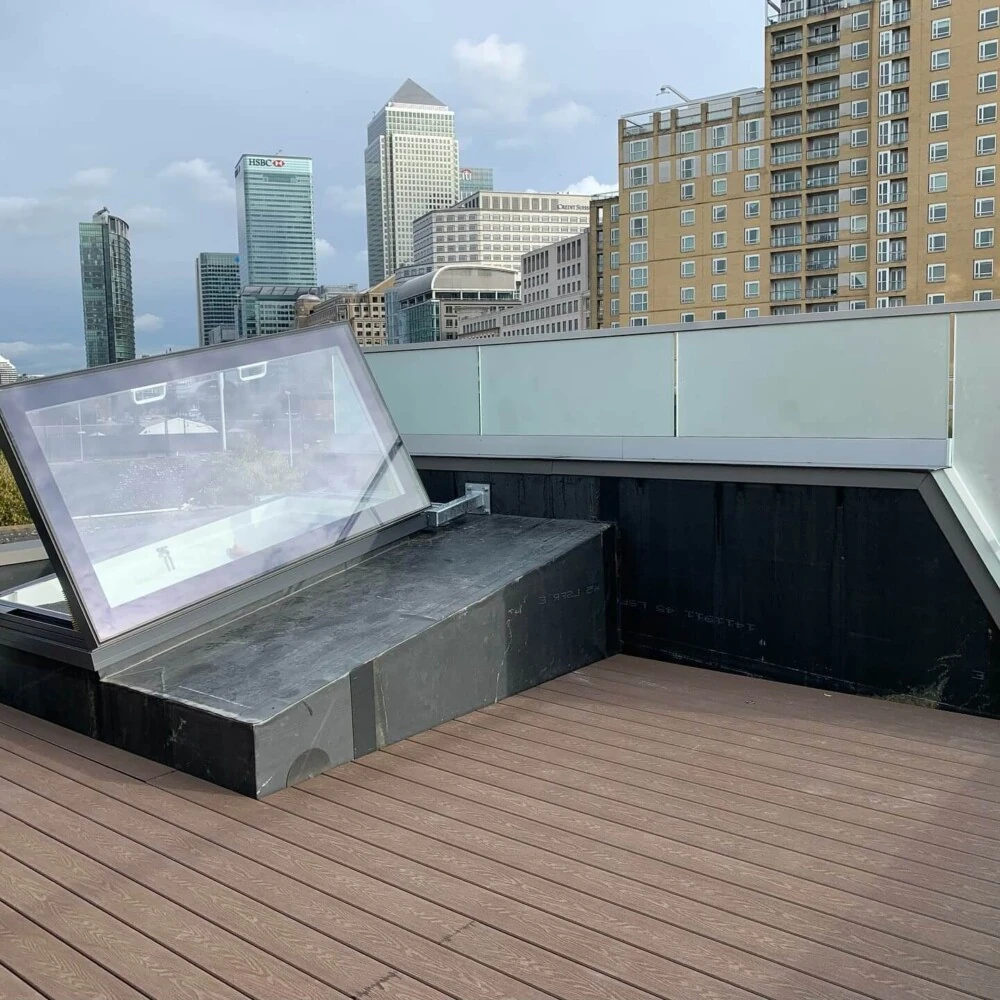 Glass roof access hatch and decking on a London roof terrace with Canary Wharf behind