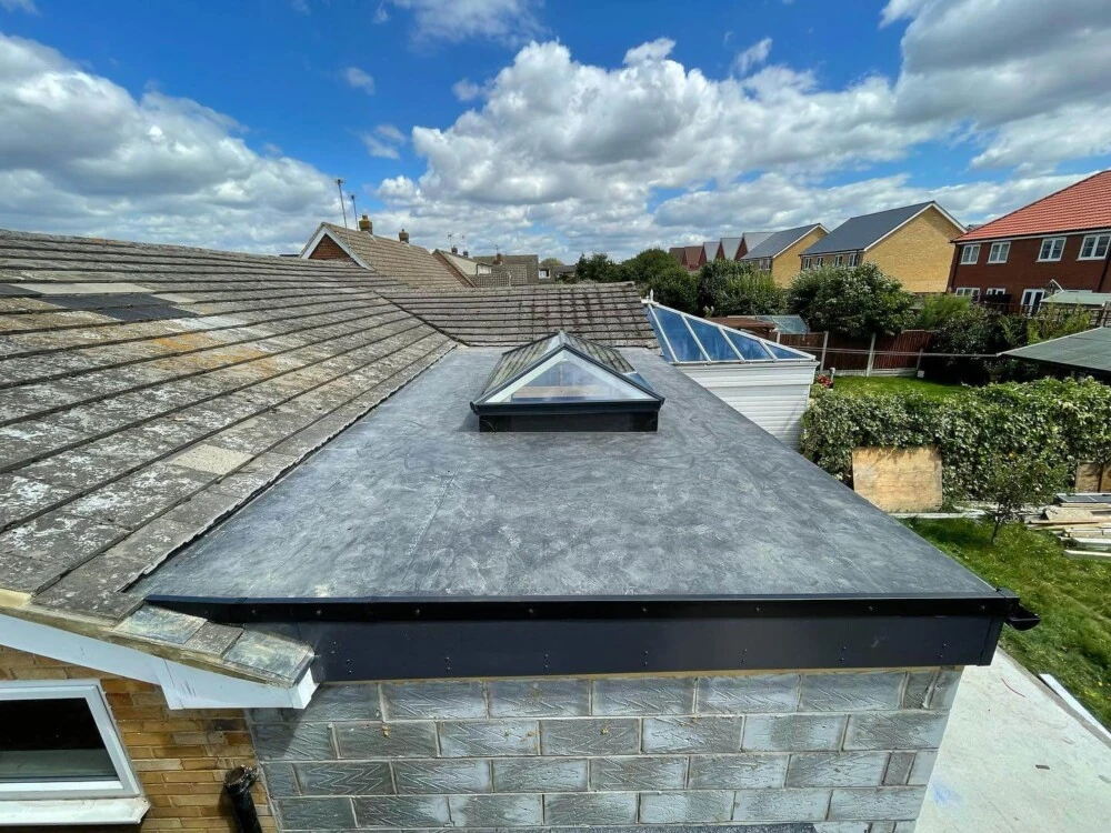 New grey flat roof with pyramid glass roof lantern on a brick extension