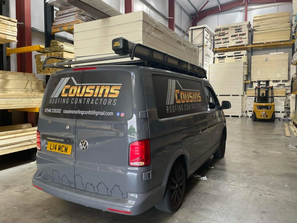 Cousins Roofing Contractors van parked inside a timber warehouse with stacked building materials
